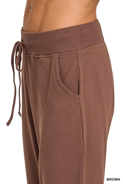 Close-up of brown women’s jogger pants with an elastic waistband, drawstring, and side pocket.