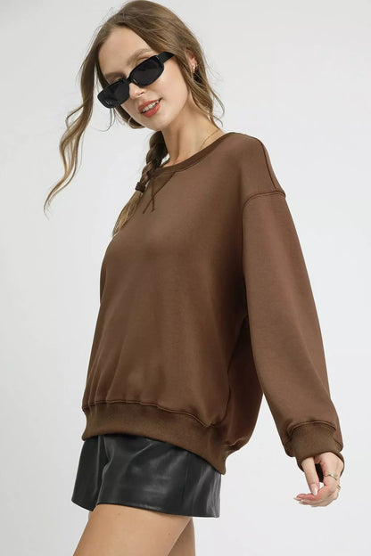 Woman wearing mocha brown oversized sweatshirt and black faux leather shorts