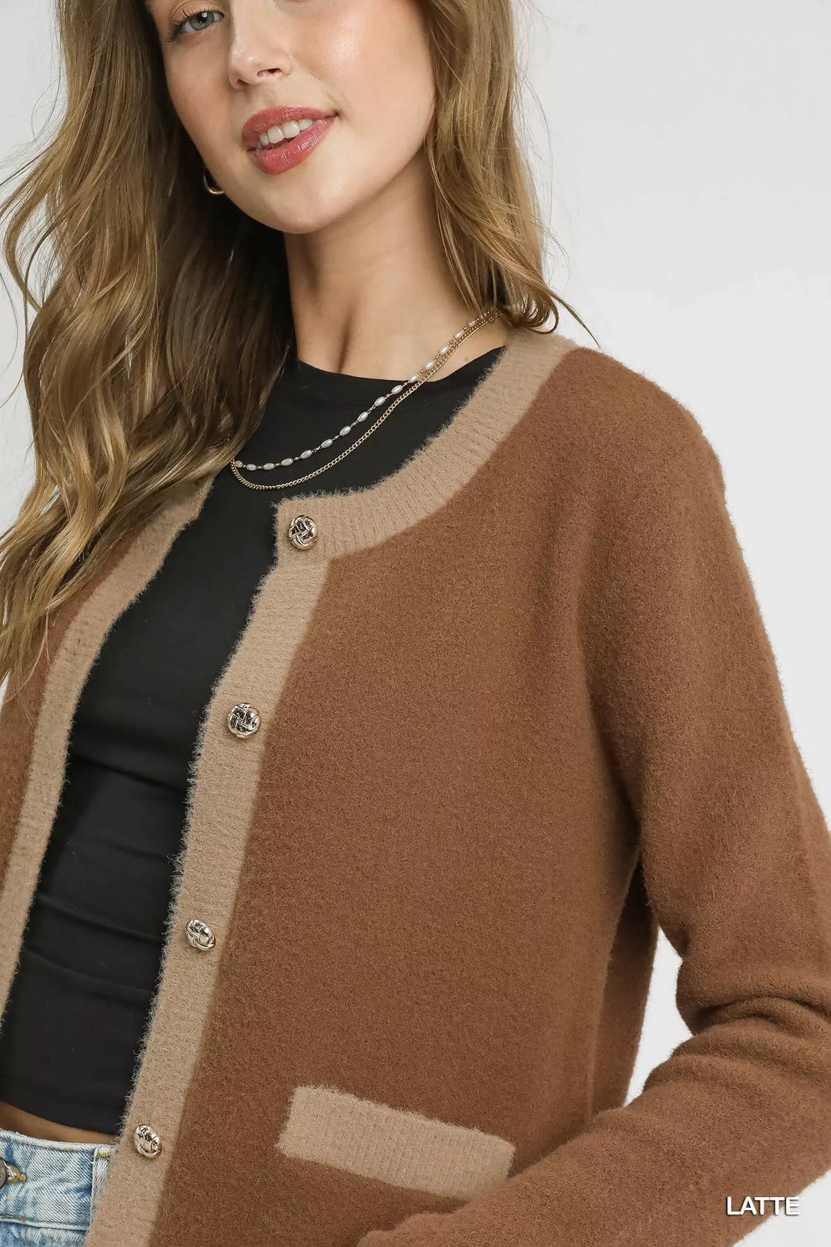 Woman wearing a two-tone brown button-up cardigan with black top and layered necklaces