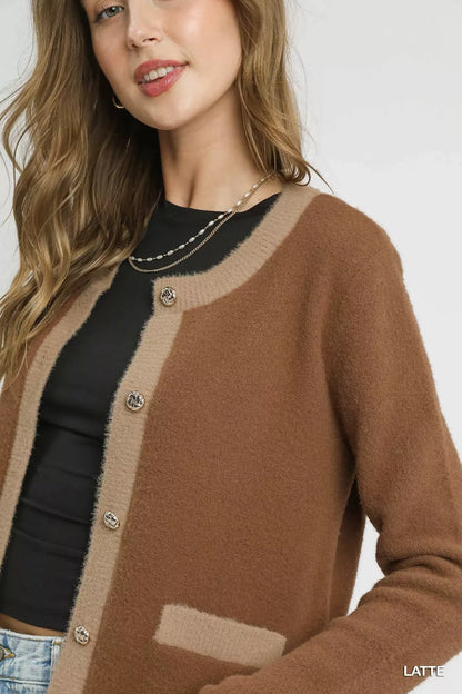 Woman wearing a two-tone brown button-up cardigan with black top and layered necklaces