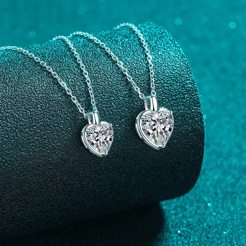 Silver heart-shaped crystal pendant necklaces on textured teal background