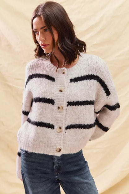 Woman wearing a white button-up sweater with black horizontal stripes and blue jeans