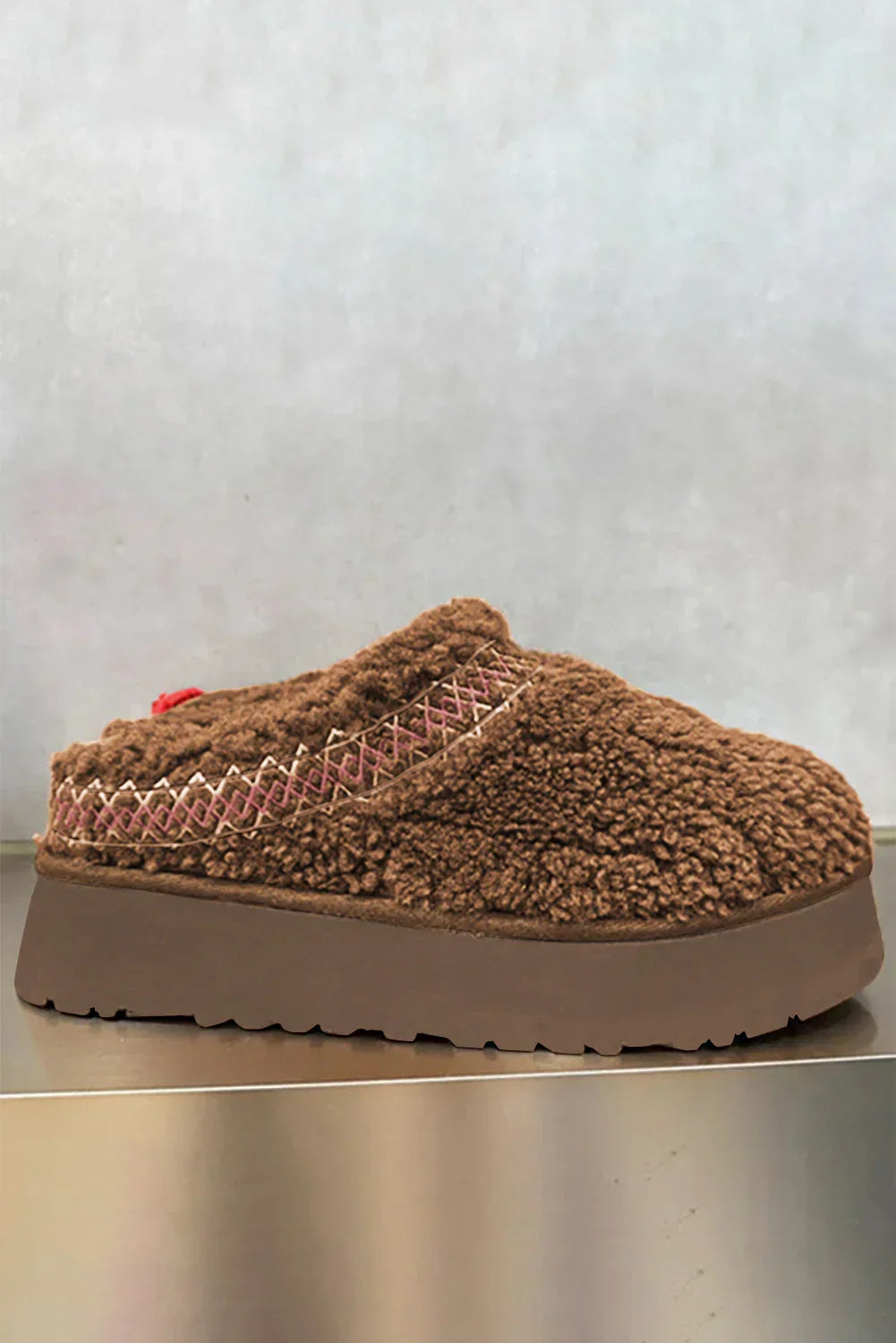 Brown sherpa slip-on clog with embroidered trim and platform sole on neutral background