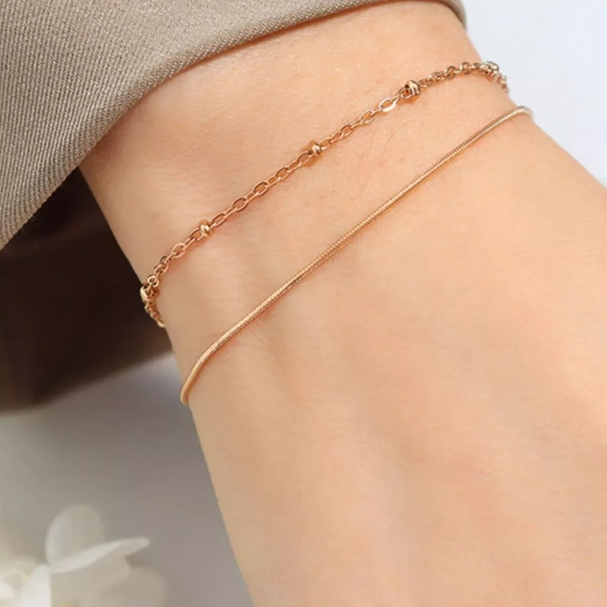 Delicate gold chain bracelets on a woman's wrist, minimalist jewelry style