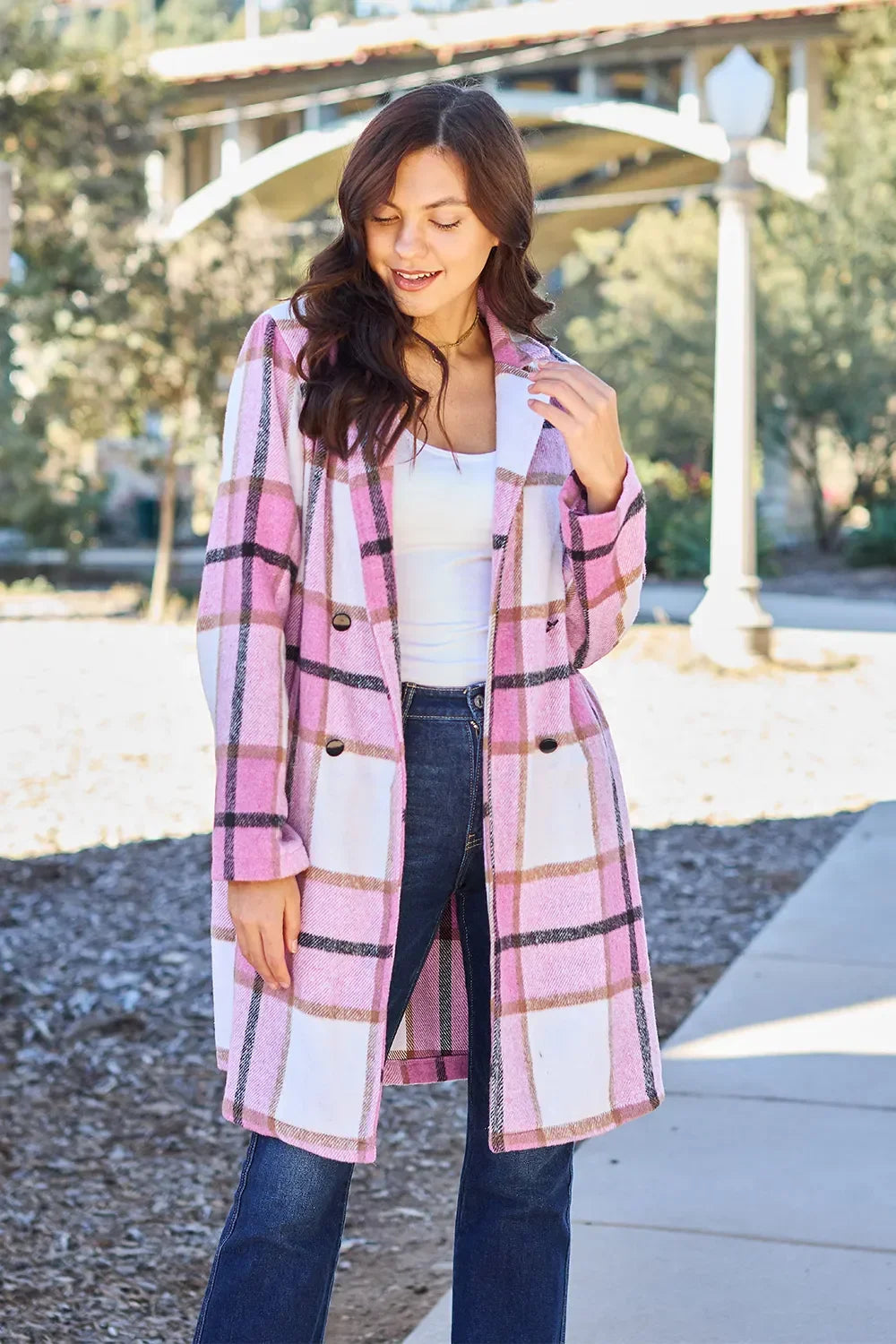 Woman wearing a pink and white plaid coat with double-breasted buttons outdoors