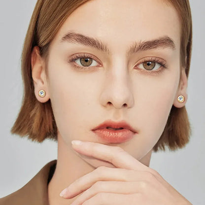 Woman with short hair wearing gold stud earrings with clear center stones