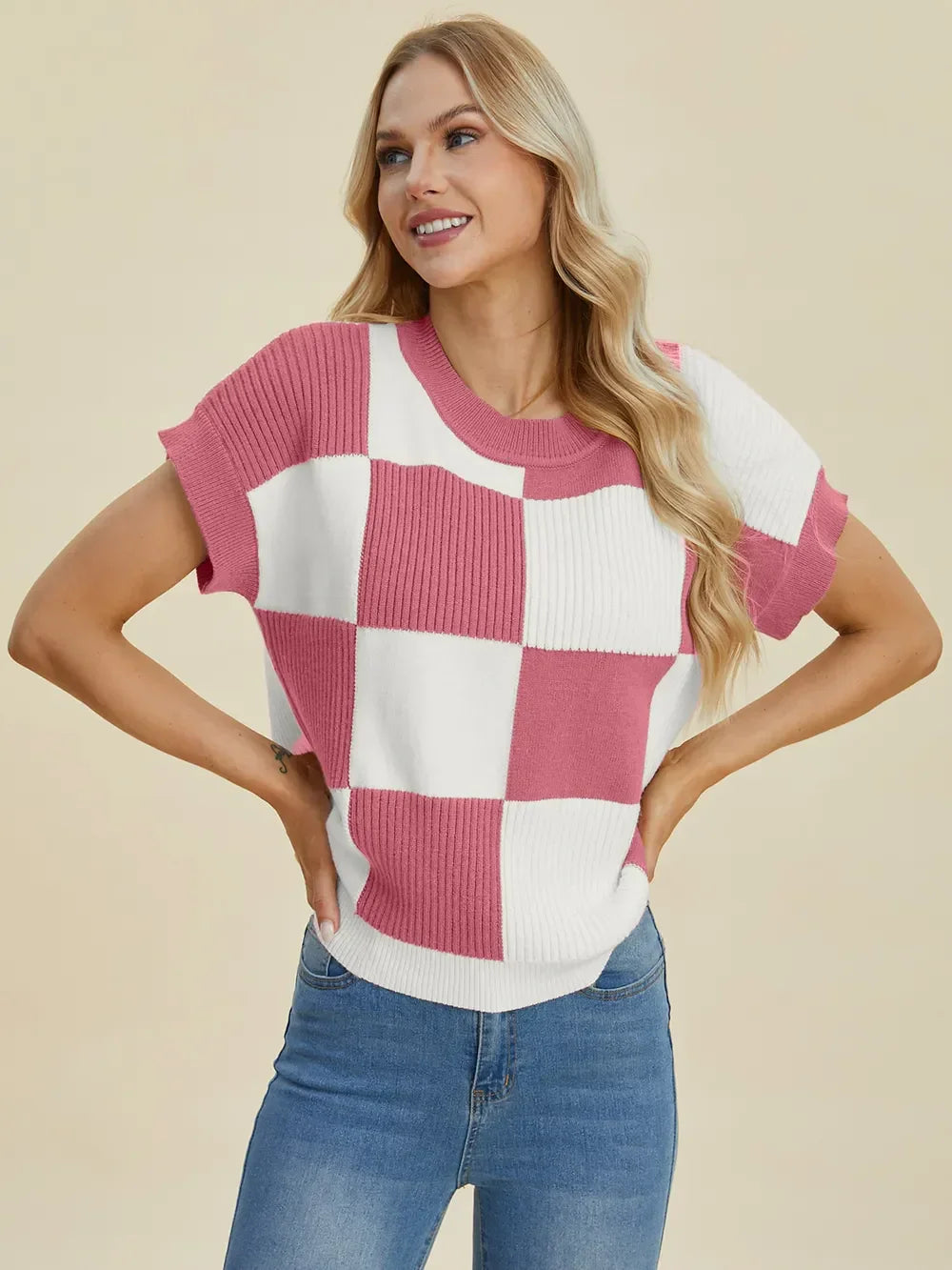 Woman wearing a pink and white checkered short-sleeve knit top with blue jeans