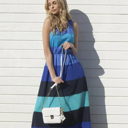 Woman in striped blue maxi dress holding a small white leather handbag with gold chain