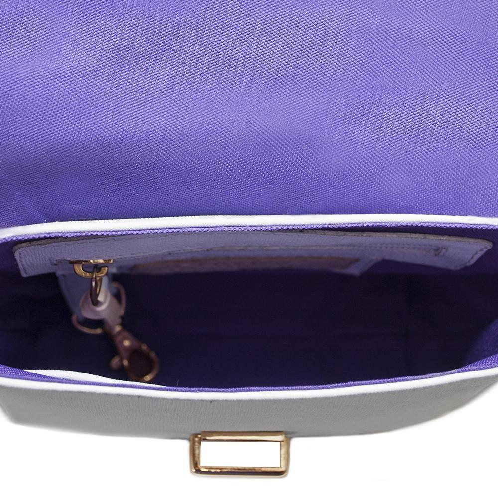 Interior view of a small white leather handbag with purple lining, gold clasp, and inner pocket.