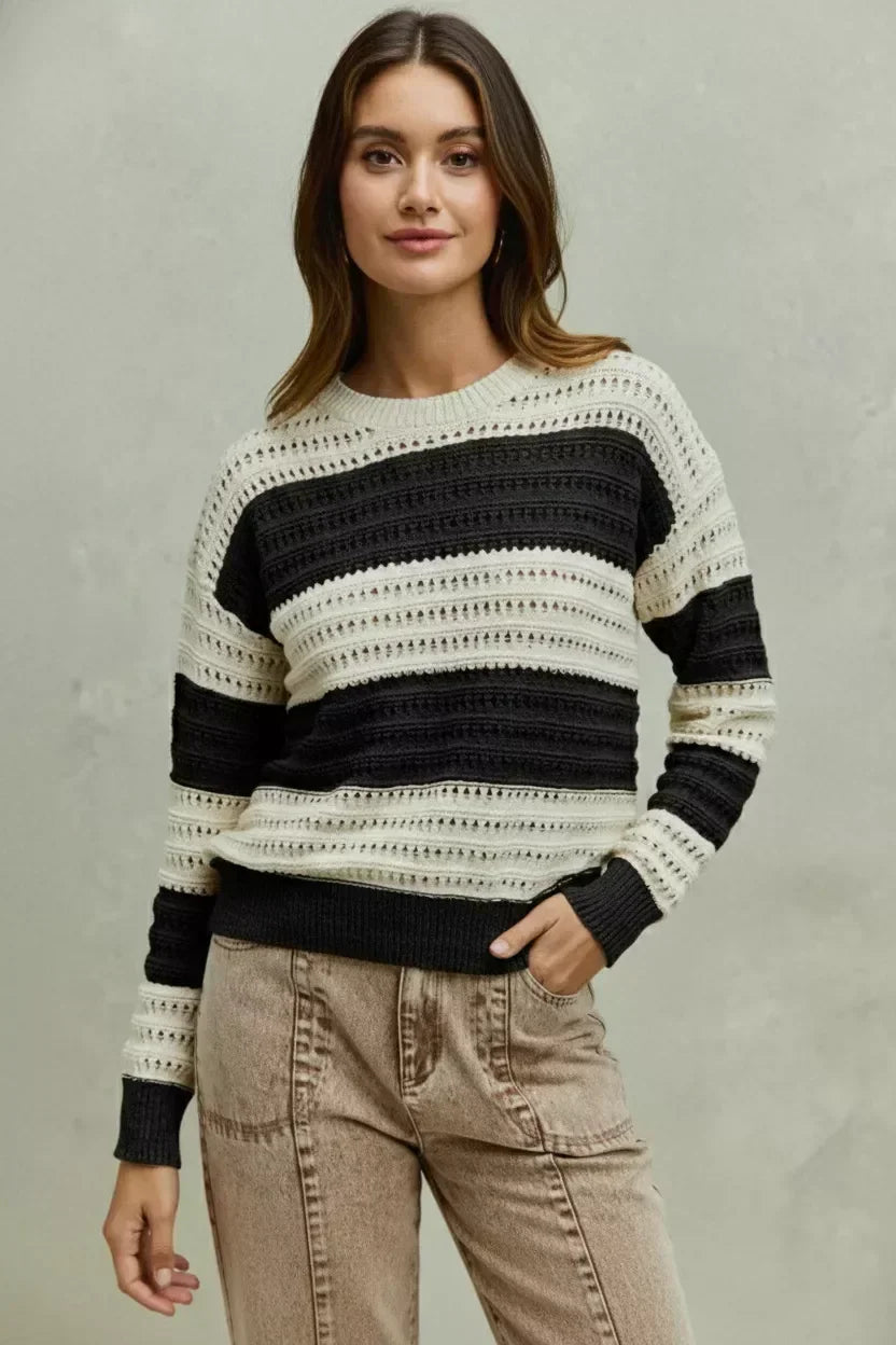 Woman wearing a black and cream striped knit sweater with relaxed beige pants