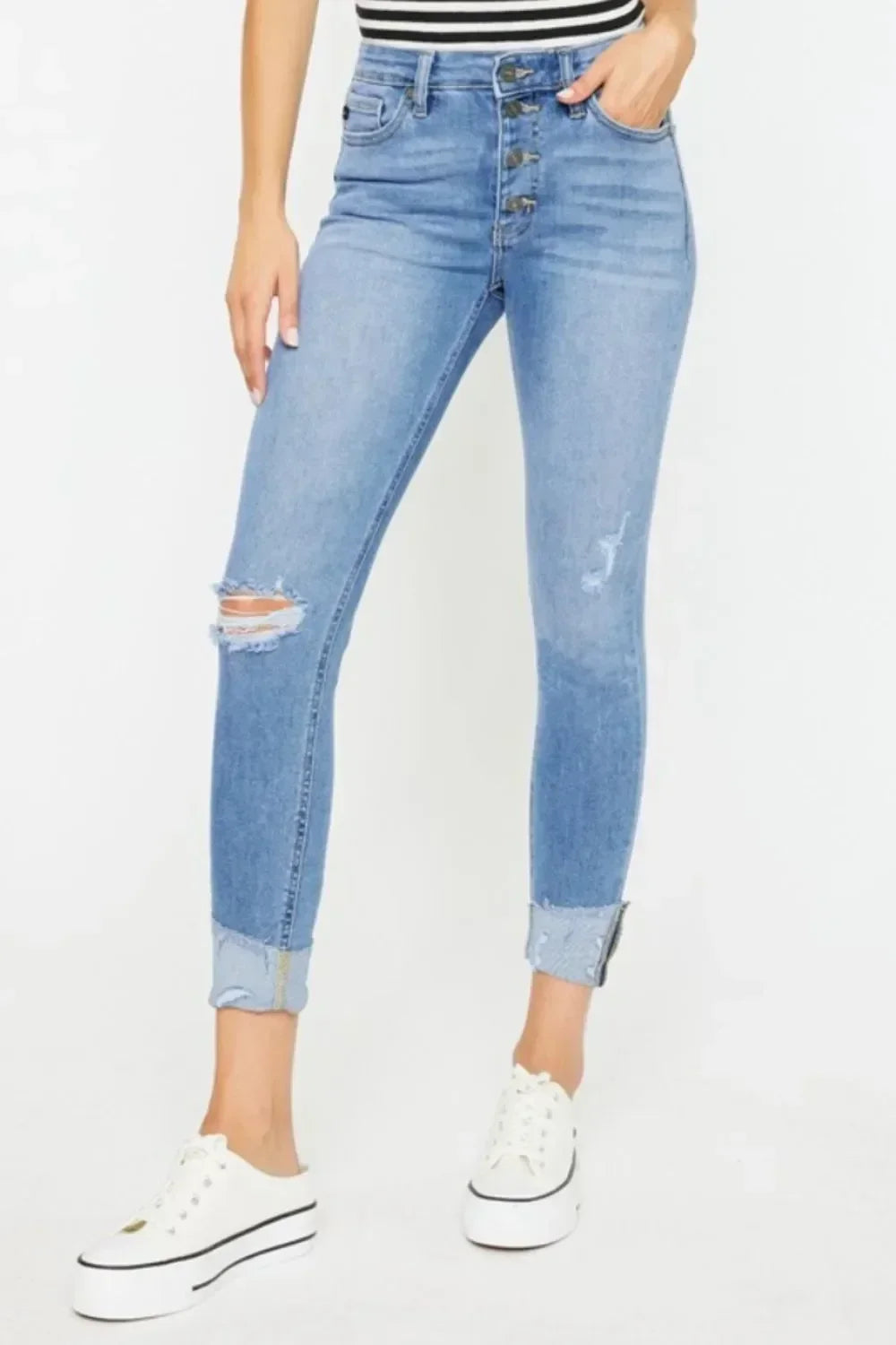 Woman wearing light wash high-rise distressed jeans with button fly and cuffed hems