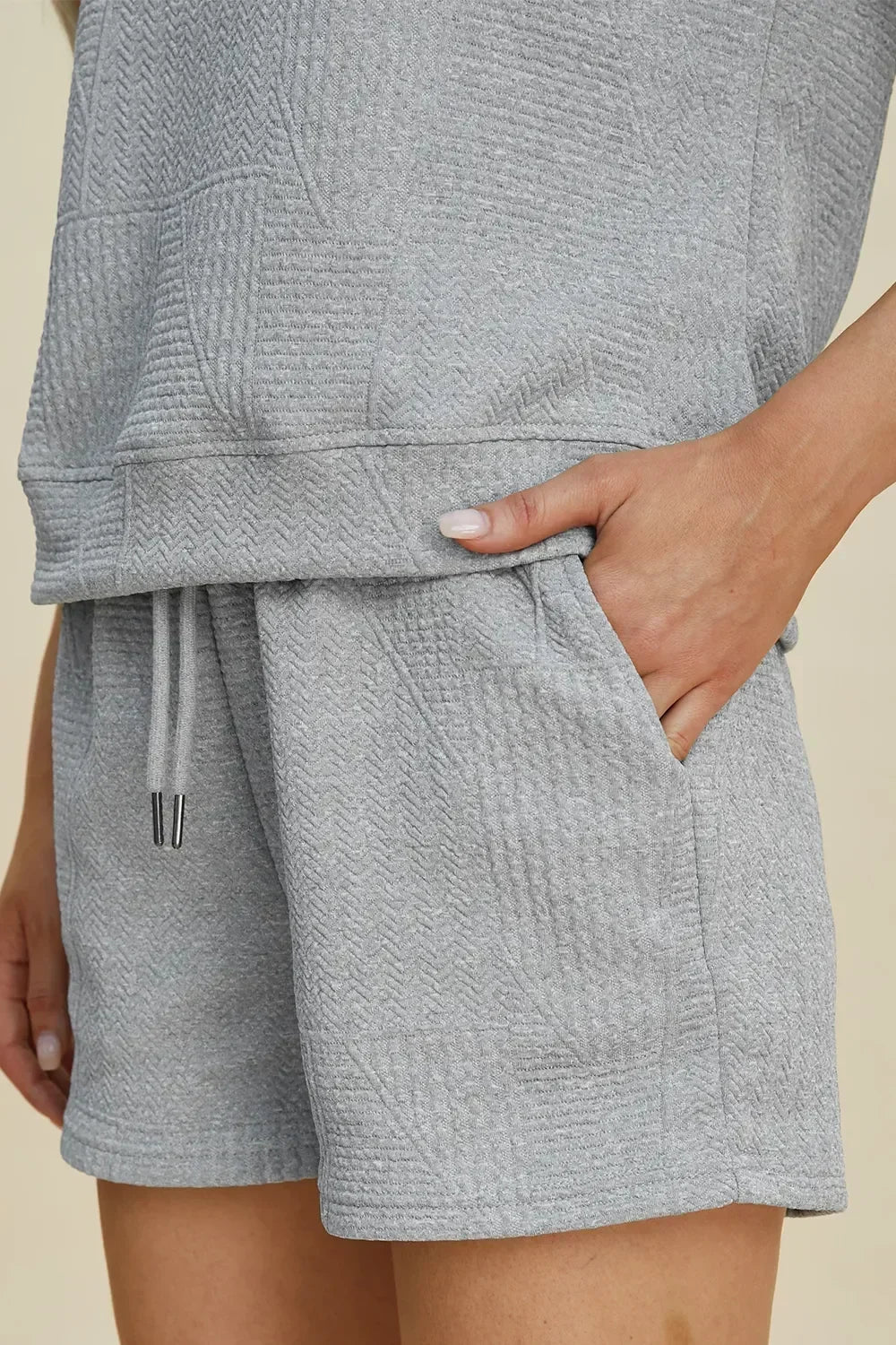 Close-up of women's light grey textured lounge shorts with drawstring waist and hand in pocket