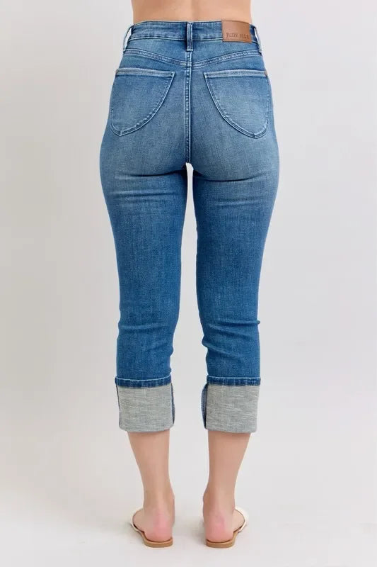 Rear view of cropped blue cuffed jeans with relaxed fit, shown on a model.