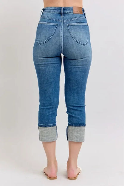 Rear view of cropped blue cuffed jeans with relaxed fit, shown on a model.
