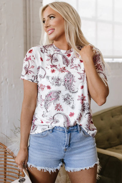 Woman in white paisley print t-shirt and light blue denim shorts in a bright room