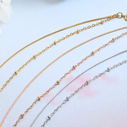 Minimalist gold, rose gold, and silver chain necklaces with delicate detailing on white background.