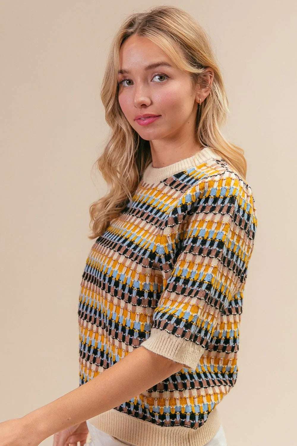 Woman wearing a short-sleeve, multicolored geometric knit sweater with relaxed fit