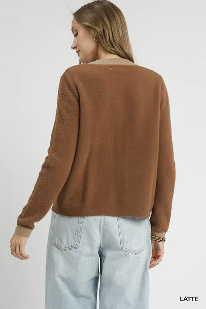 Woman wearing a brown textured sweater and light blue jeans, back view, minimal background