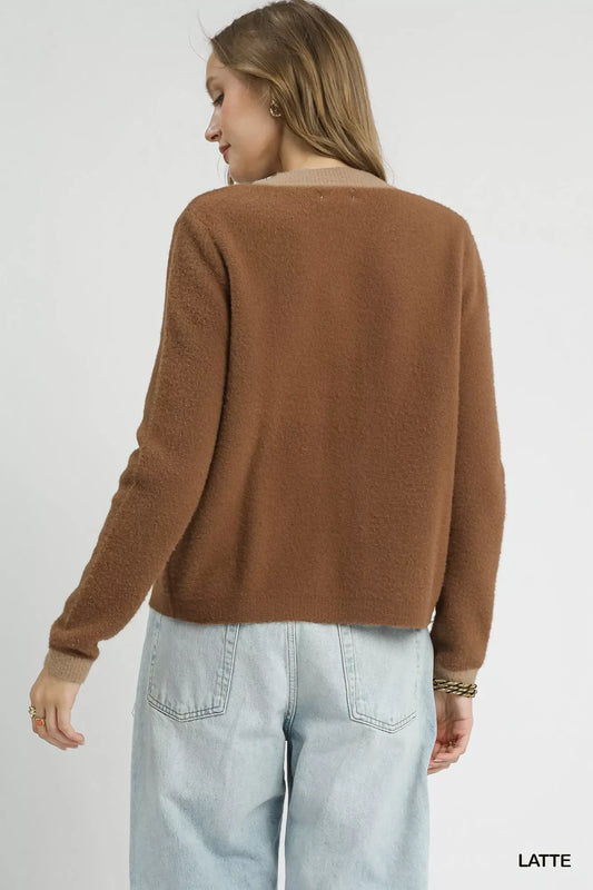 Woman wearing a brown textured sweater and light blue jeans, back view, minimal background