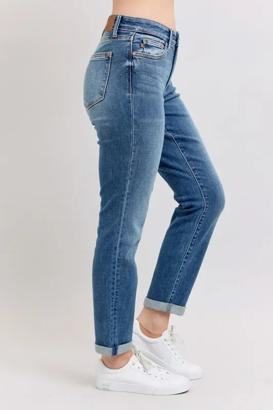 Woman wearing high-rise blue straight-leg jeans with rolled cuffs and white sneakers