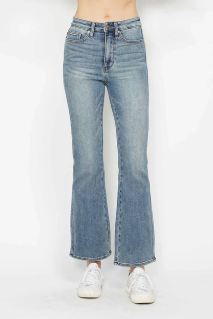 Woman wearing high-waisted, straight-leg blue jeans with white sneakers