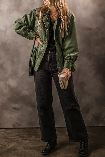 Woman wearing green utility jacket, black jeans, black lace-up boots, holding coffee cup