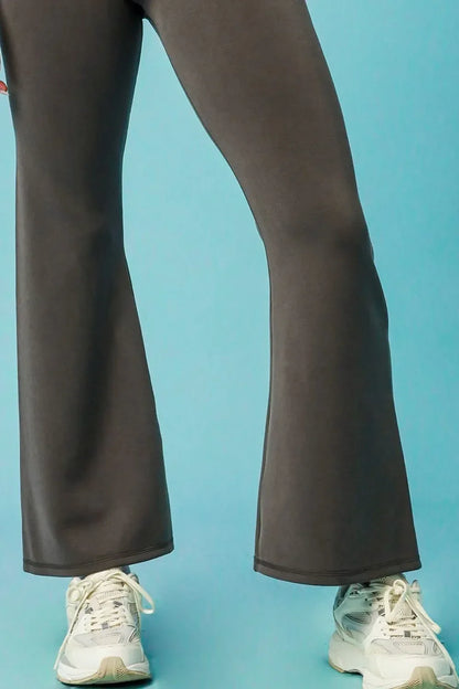 Charcoal flared pants with relaxed fit, paired with white sneakers, on blue background