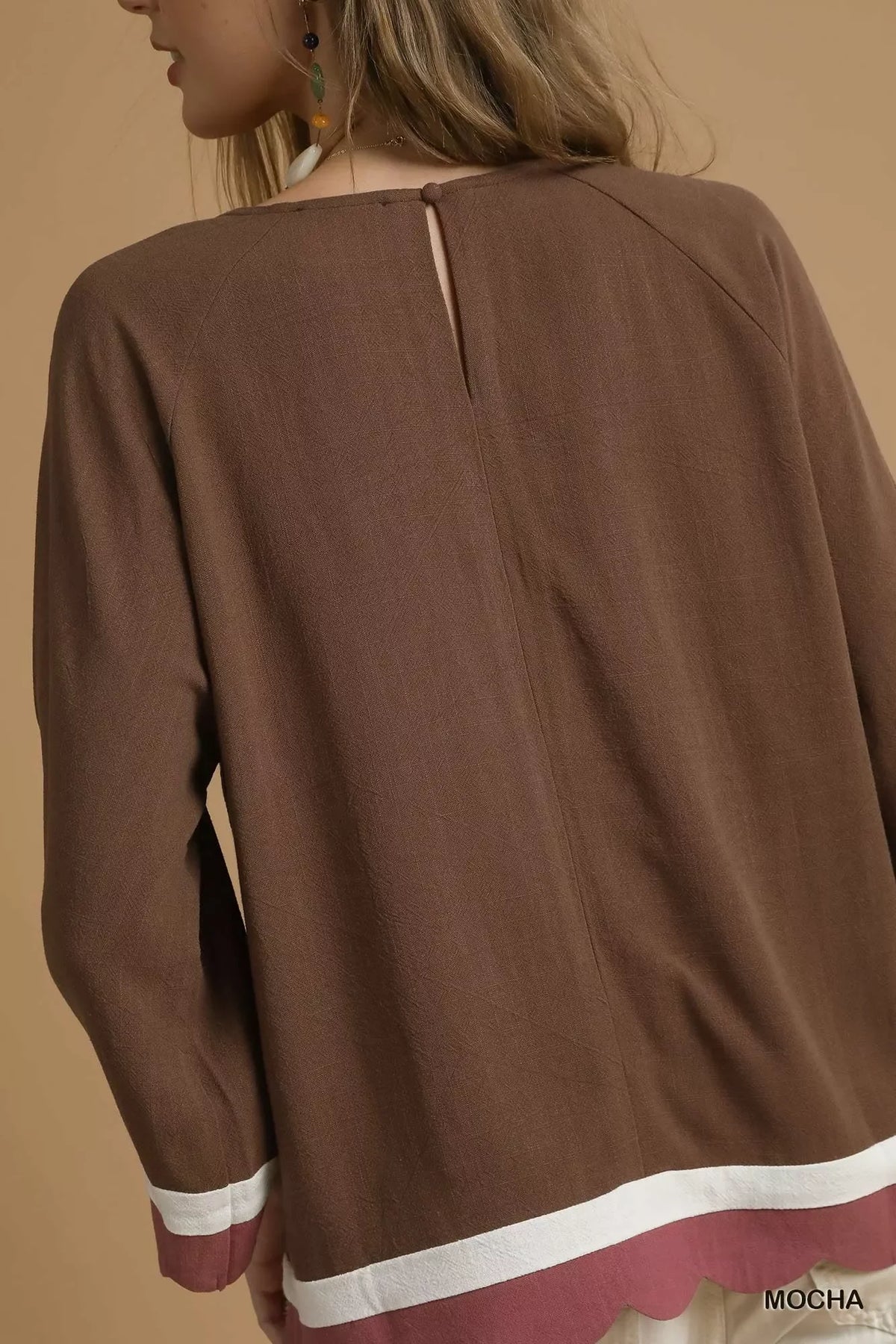 Back view of a brown long sleeve blouse with white and mauve trim, keyhole neckline