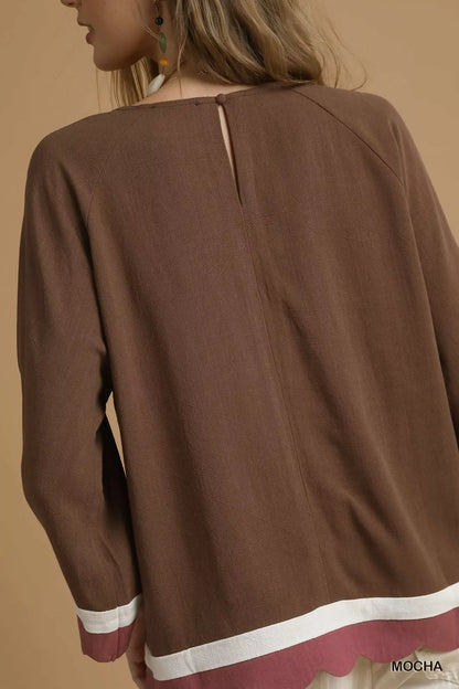 Back view of a brown long sleeve blouse with white and mauve trim, keyhole neckline