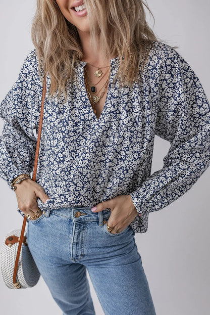 Woman wearing a blue floral blouse with light wash jeans and layered gold necklaces