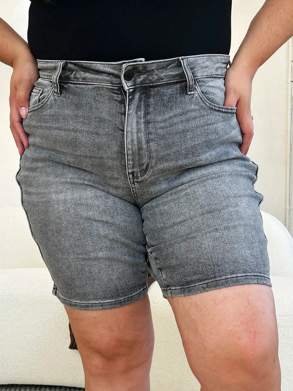 Woman wearing high-waisted gray denim shorts with five-pocket design and black top