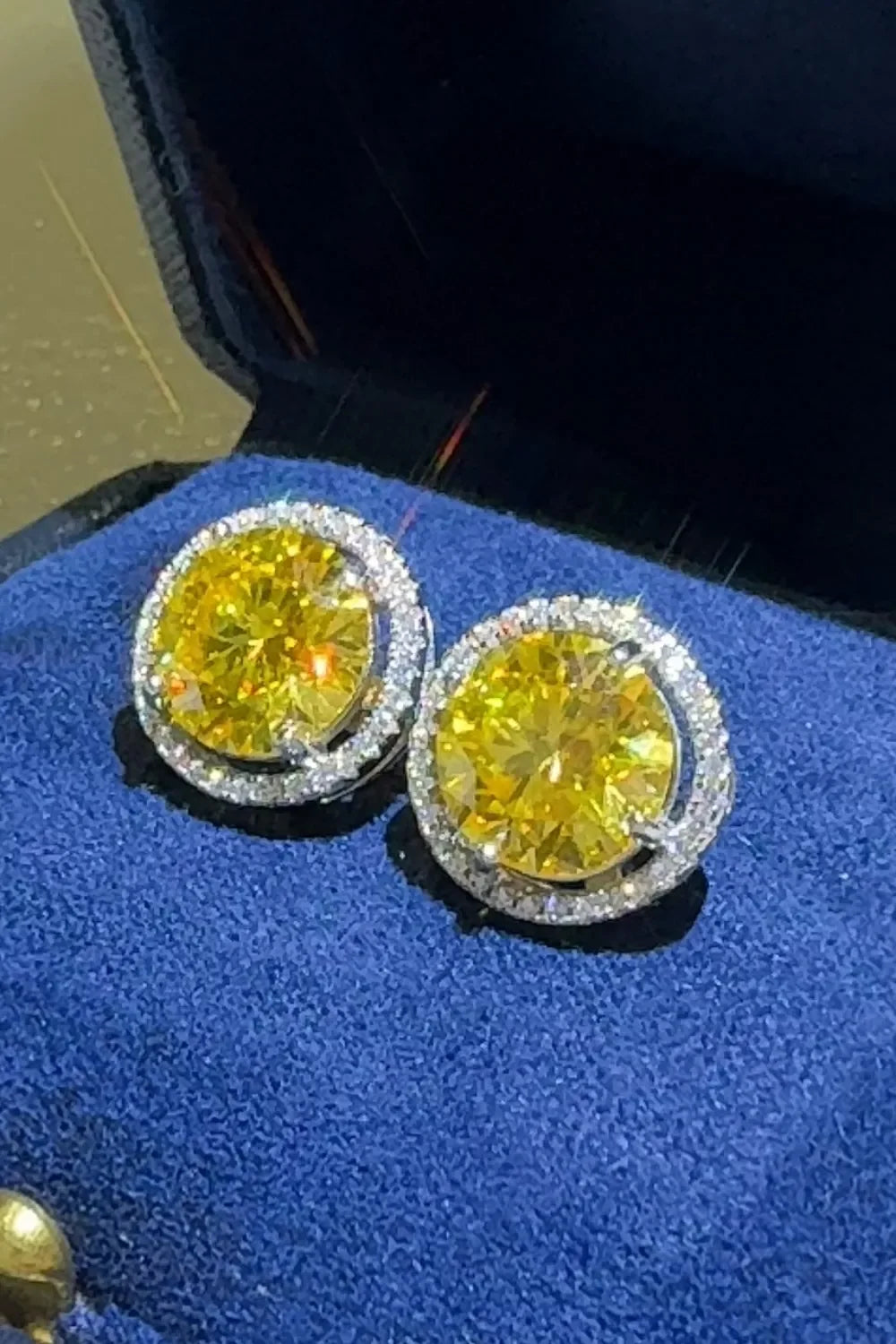 Yellow gemstone stud earrings with diamond halos in blue velvet jewelry box