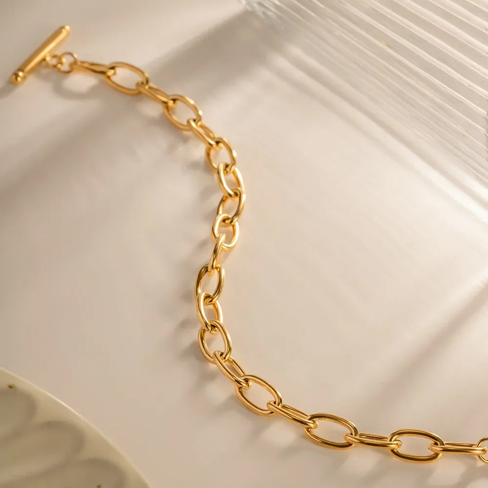Gold chain link bracelet with toggle clasp on a neutral background, modern jewelry
