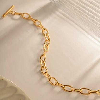 Gold chain link bracelet with toggle clasp on a neutral background, modern jewelry