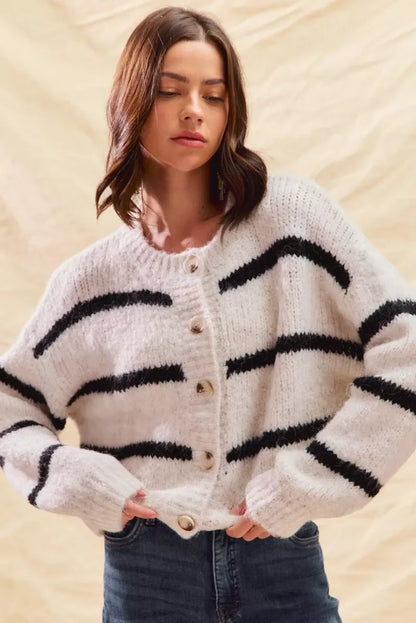 Woman wearing a cozy white button-up sweater with black stripes and relaxed fit jeans