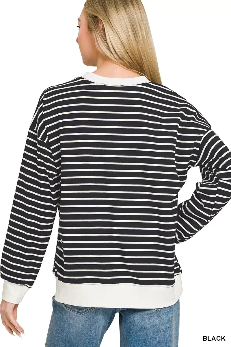 Woman wearing black and white striped long sleeve top with relaxed fit and blue jeans