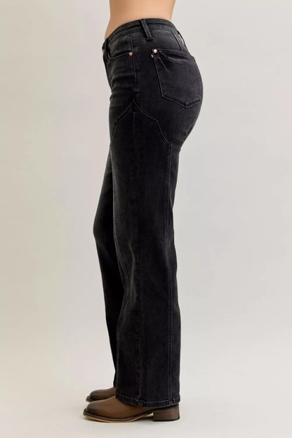 Side view of high-waisted black straight leg jeans with brown ankle boots on a model