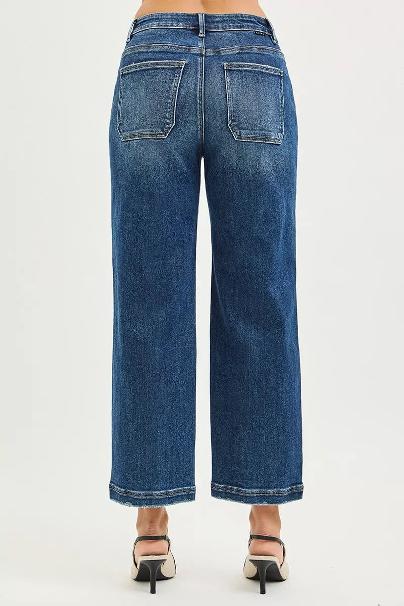 Back view of wide-leg blue denim jeans with raw hem and high waist on model