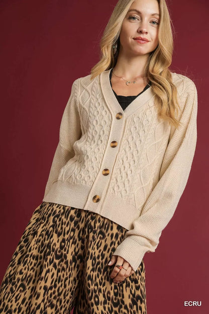 Woman wearing an ecru cable knit cardigan with brown buttons and leopard print skirt