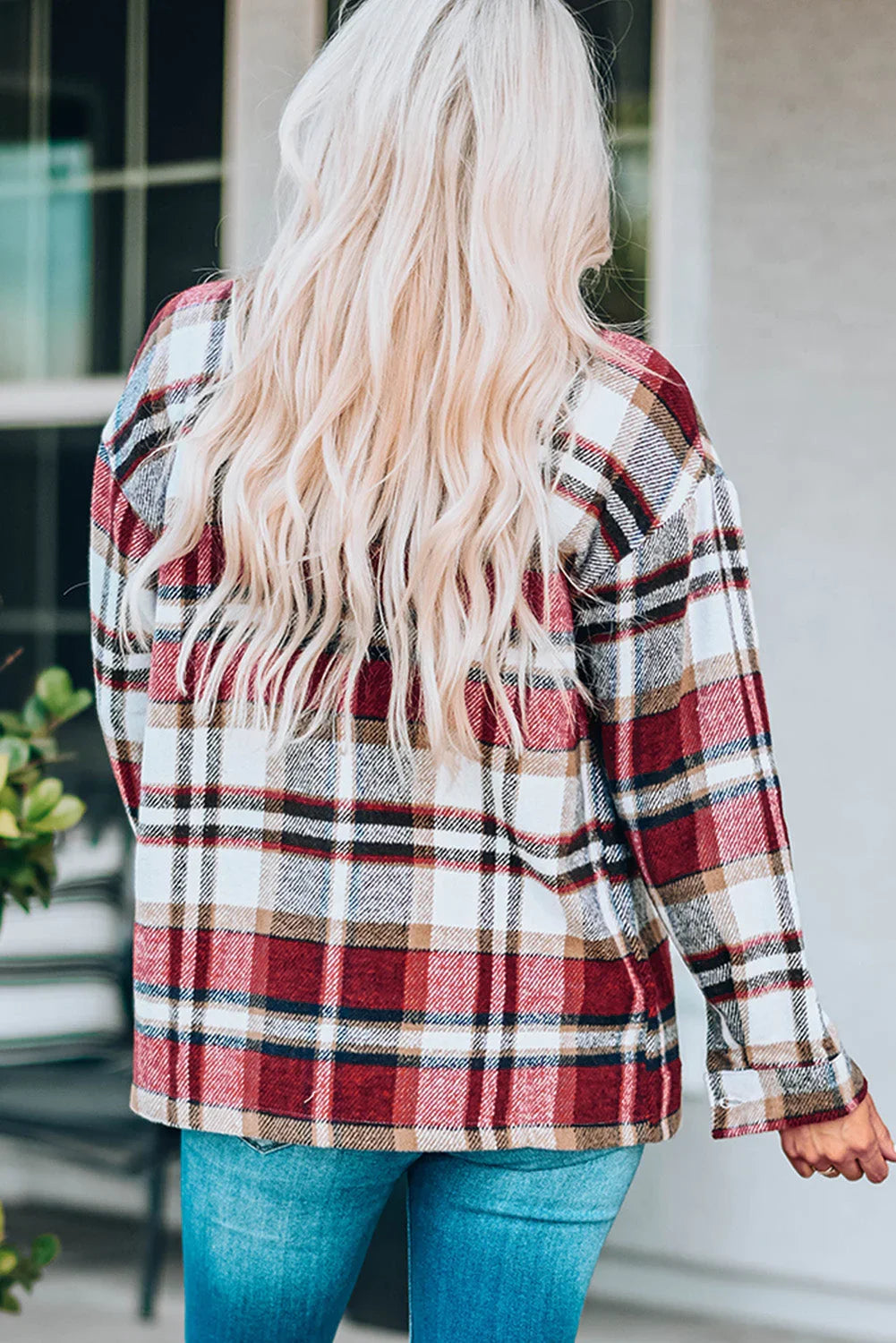 Woman wearing a red plaid flannel shirt and blue jeans, viewed from behind