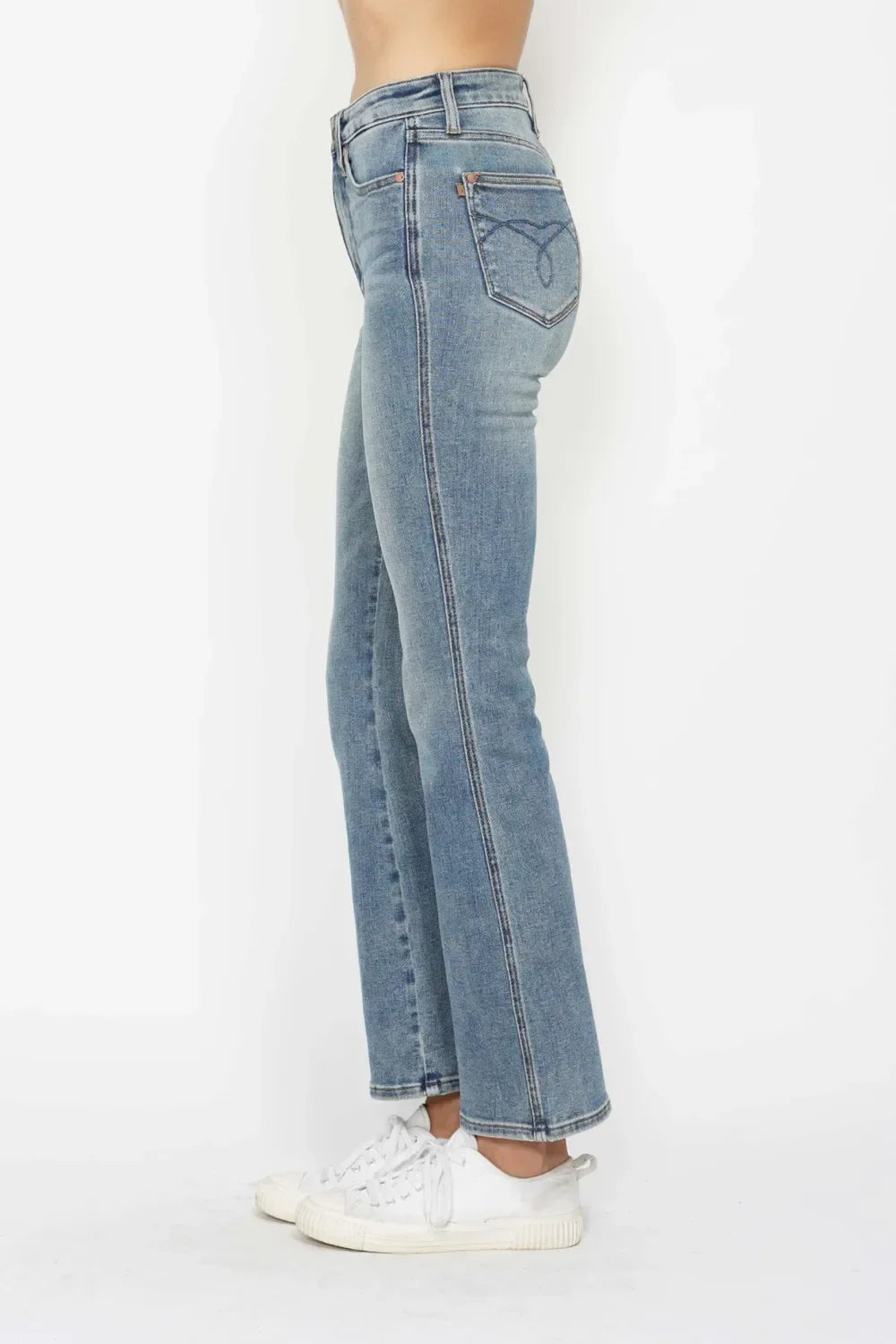 Side view of woman wearing high-waisted straight leg blue jeans and white sneakers