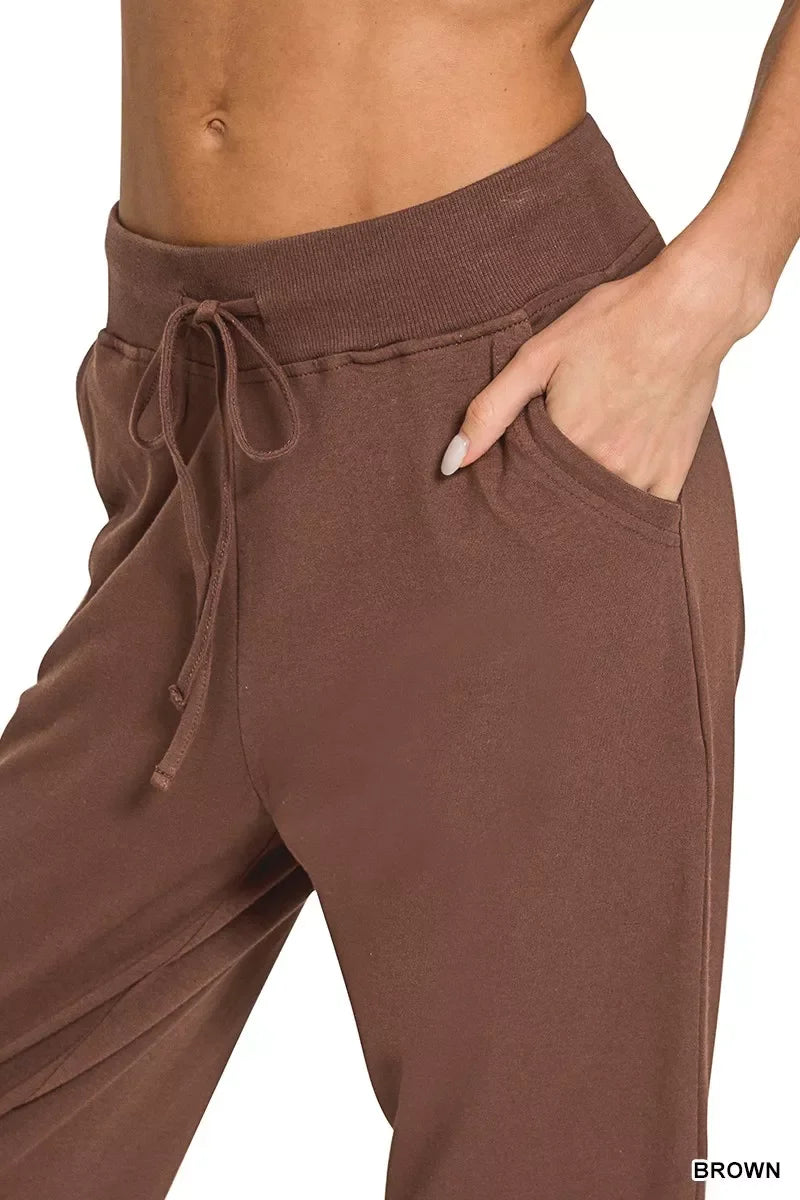 Close-up of brown women's lounge pants with drawstring waist and hand in pocket.