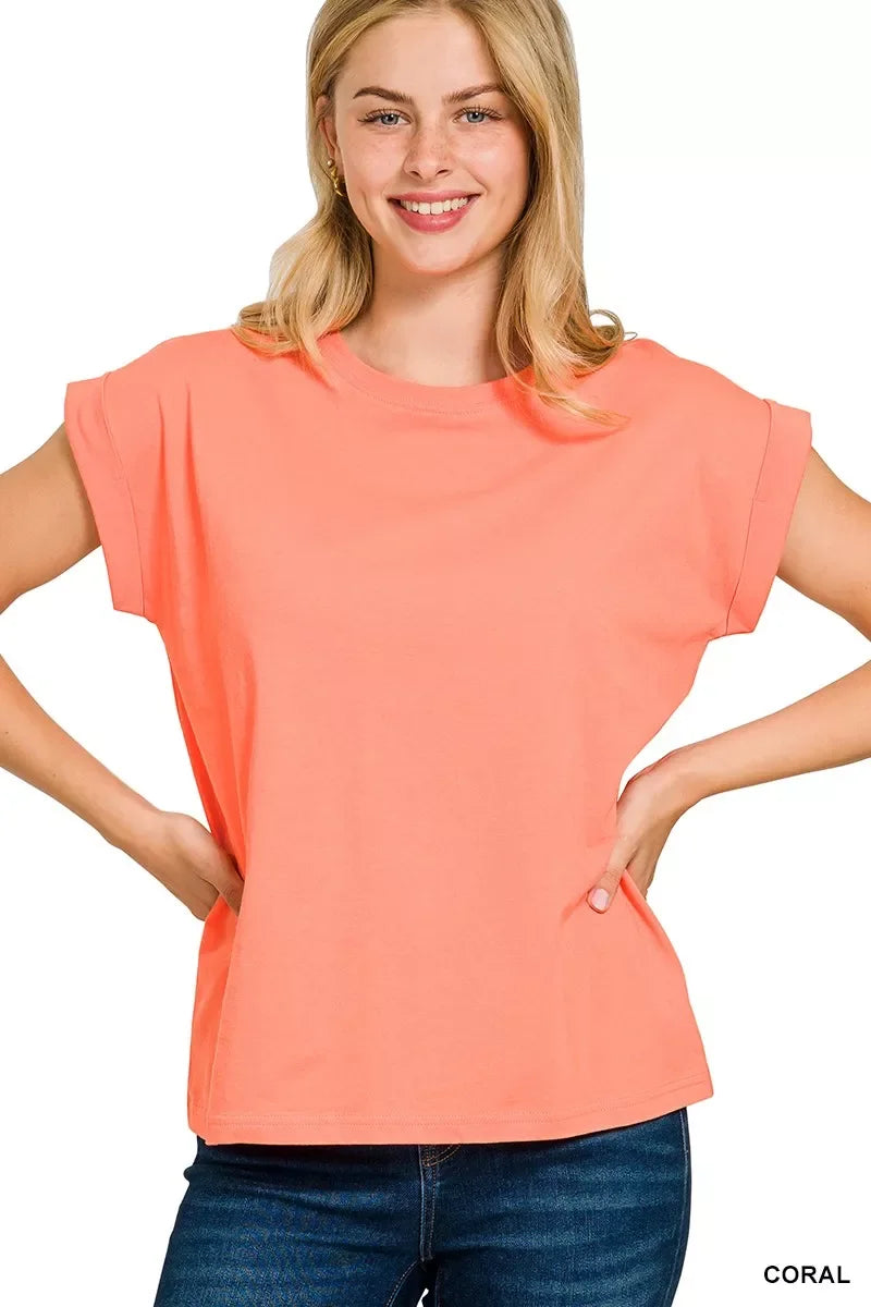 Woman wearing relaxed fit coral short sleeve t-shirt and blue jeans against white background.