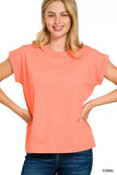 Woman wearing relaxed fit coral short sleeve t-shirt and blue jeans against white background.