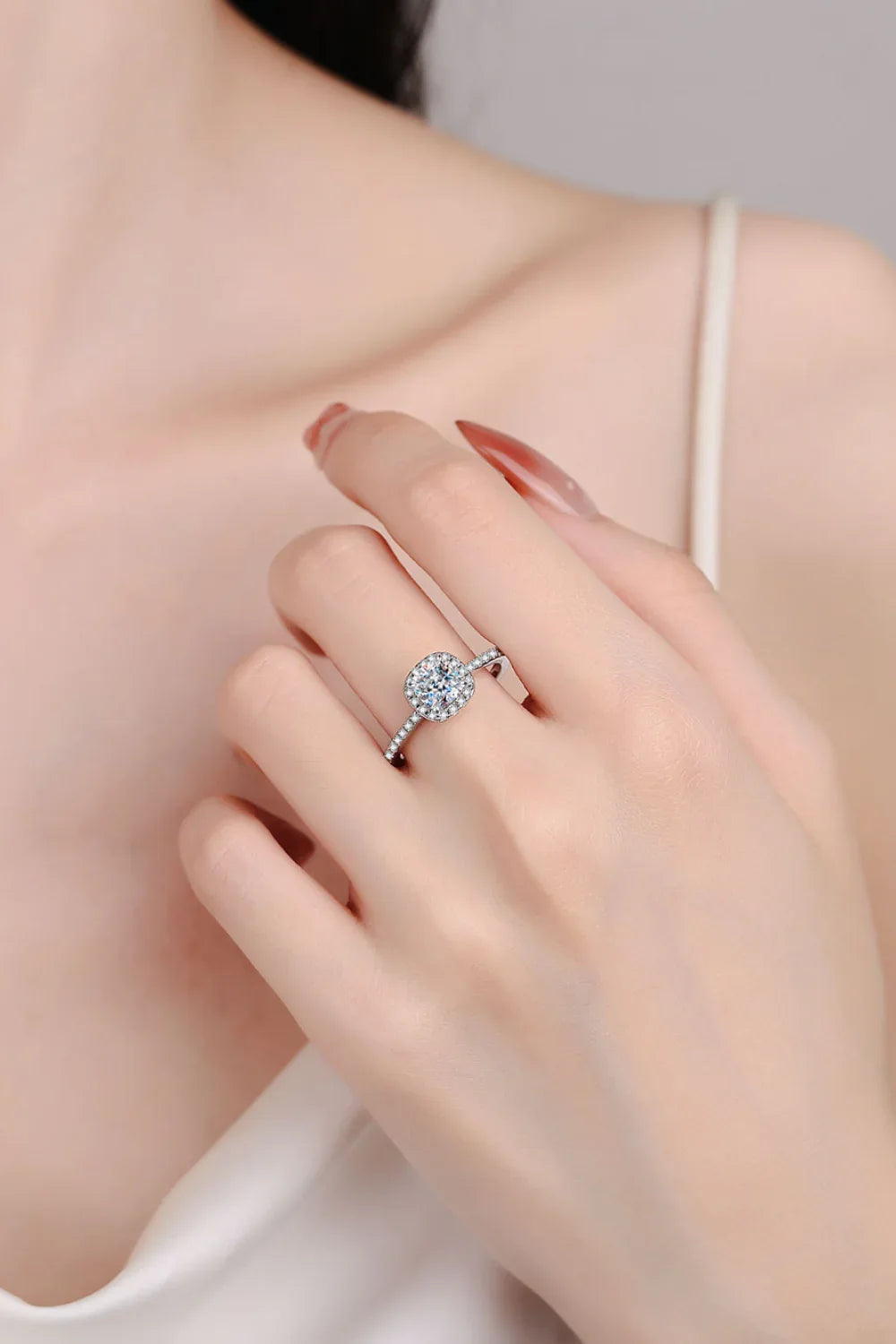 Woman wearing an elegant solitaire diamond ring with a pavé band, closeup on hand