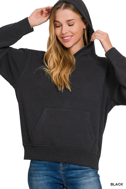 Woman wearing black oversized hoodie with kangaroo pocket and blue jeans on white background