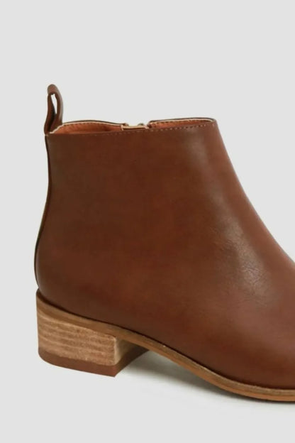 Side view of brown leather ankle boot with low stacked heel on light background