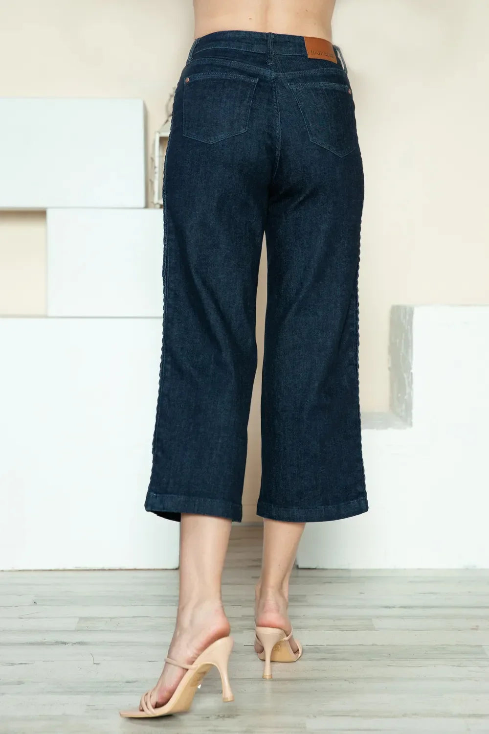 Back view of cropped dark wash wide-leg jeans and nude heeled sandals