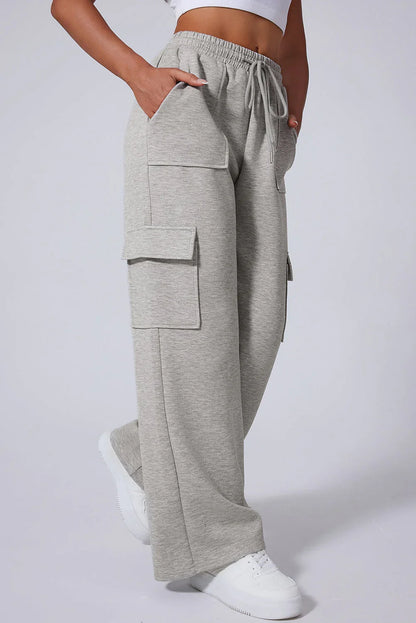Light grey wide-leg cargo sweatpants with flap pockets, elastic waist, and white sneakers