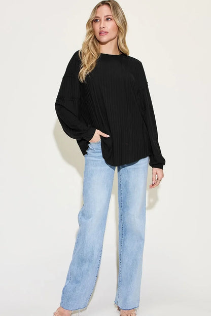Woman wearing a relaxed black long sleeve blouse and light wash wide-leg jeans